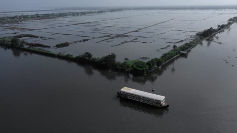 two-boards-taking-place-in-the-middle-of-the-water,-a-boat-is-standing-quietly-on-the-shore-and-a-wat-is-going-full-of-people-and-where-at-the-back-there-are-many-different-coconut-trees