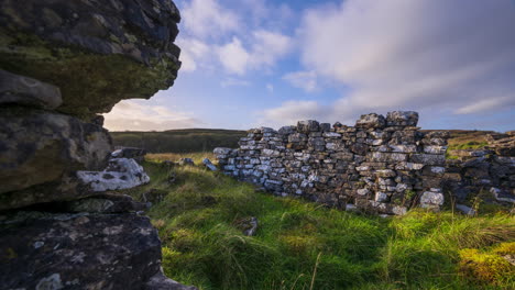 Timelapse-of-rural-nature-farmland-with-abandoned-old-house-ruins-in-the-foreground-in-grass-field-during-sunny-cloudy-day-viewed-from-Carrowkeel-in-county-Sligo-in-Ireland