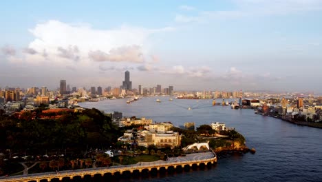 Golden-hour-over-bustling-port-city-skyline-with-busy-shipping-lanes,-aerial-view