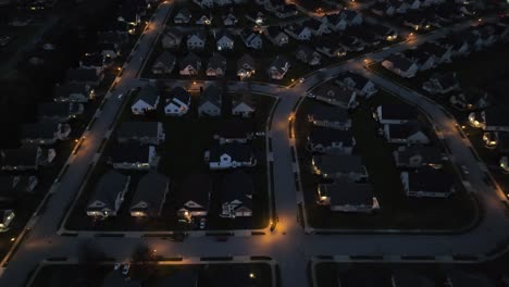 Nighttime-aerial-shot-of-a-residential-neighborhood-with-lit-streets-and-houses