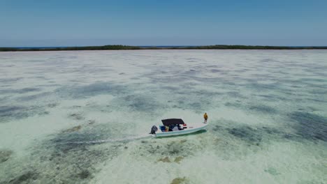 A-small-fishing-boat-with-a-guide-at-the-bow-in-the-clear-waters-of-los-roques,-aerial-view