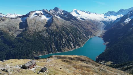 Olpererhutte-Hut-and-Mountain-Lake-Schlegeis-in-Zillertal-Alps,-Austria---Aerial-4k-Circling