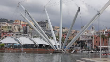 Establishing-clip-over-old-Genoa-Port,-Porto-Antico,-in-Italy-showing-peaceful-waterway-and-striking-architecture