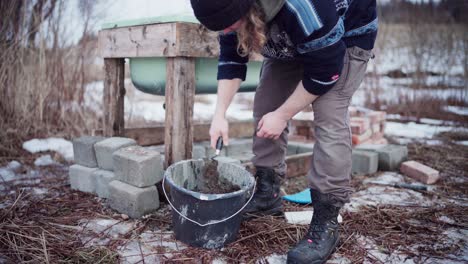 The-Man-is-Blending-the-Cement-in-the-Bucket-Required-for-Constructing-a-DIY-Hot-Tub---Close-Up