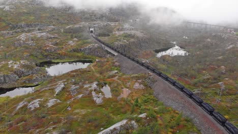 Aérea:-Tren-De-Mineral-En-Søsterbekk-Stasjon,-Cerca-De-La-Frontera-Entre-Suecia-Y-Noruega,-En-El-Norte-De-Laponia,-Entrando-En-Un-Túnel