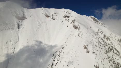 Pico-La-Om-Cubierto-De-Nieve-En-Las-Montañas-Piatra-Craiului-Bajo-Un-Cielo-Azul-Claro,-Vista-Aérea