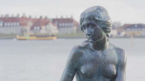 Telephoto-zoom-on-iconic-The-Little-Mermaid-statue-with-boat-passing-in-back