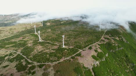 Drone-flight-over-spinning-wind-turbines-on-cloudy-lush-Madeira-mountain-hill