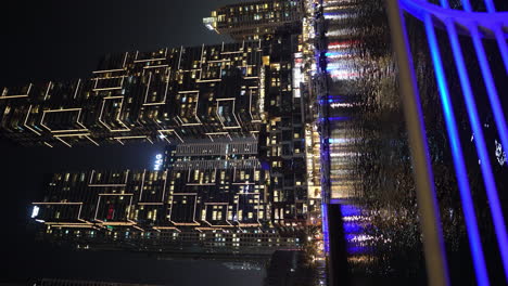Video-Vertical:-Puerto-Deportivo-De-Dubai-Por-La-Noche,-Edificios-Brillantes-Y-Reflejo-De-Luz-En-El-Agua,-Emiratos-Árabes-Unidos