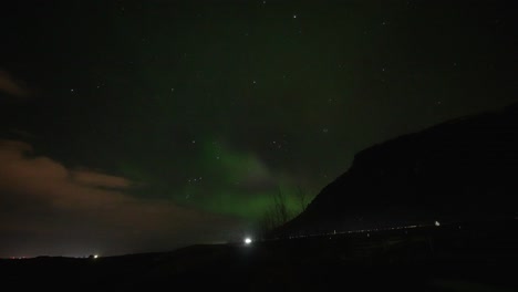 Aurora-Boreal-Parpadeante-Con-Coches-Conduciendo-Por-La-Carretera-De-Iones-Por-La-Noche-En-La-Isla-De-Islandia