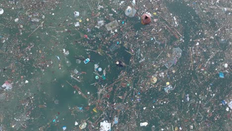 Low-altitude-top-down-drone-shot-of-polluted-water-filled-with-trash-floating-over-dead-coral-reef-in-the-turqouise-tropical-water-of-Bali-Indonesia