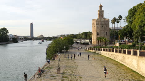 Torre-del-Oro-next-to-Guadalquivir-River,-people-around,-Seville,-Spain