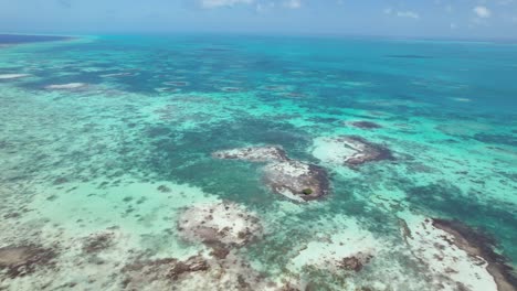 Aerial-sweep-over-the-turquoise-waters-and-coral-reefs-of-Los-Roques-during-the-day,-clear-skies