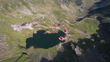 Aerial-shot-of-Balea-Lake-with-winding-Transfagarasan-road-in-the-Fagaras-Mountains-at-sunrise
