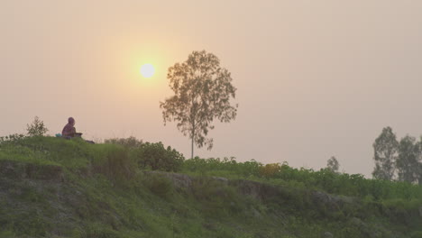 Woman-Sitting-on-top-of-a-hill-during-sunset