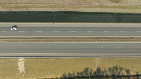 Top-down-view-of-a-single-car-on-a-wide,-empty-highway