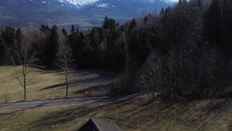 Drohnenflug-über-Einer-Kleinen-Hütte-In-Den-Bergen-Mit-Luftblick-über-Die-Stadtlandschaft-Und-Die-Schneebedeckten-Berge-In-Österreich