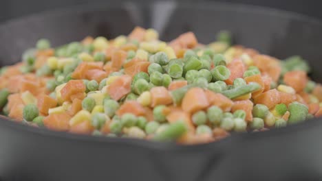 frozen-peas-and-carrot-rolling-in-to-a-pan-for-healthy-organic-vegetarian-food-diet-preparation-from-a-restaurant-chef-,-close-up-of-vegetable-ingredients