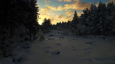 Drone-Flies-Through-Snow-Covered-Creek-At-Dusk-In-Lapland,-Finland,-Arctic-Circle