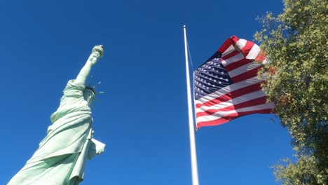 Réplica-De-La-Estatua-De-La-Libertad-Y-Bandera-Americana,-ángulo-Bajo-En-Cámara-Lenta