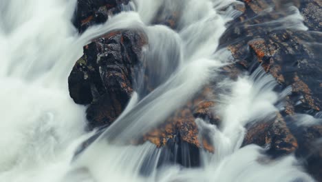 Ein-Mächtiger-Wildwasserschwall-Rauscht-über-Den-Dunklen-Felsen-Im-Langzeitbelichtungsvideo