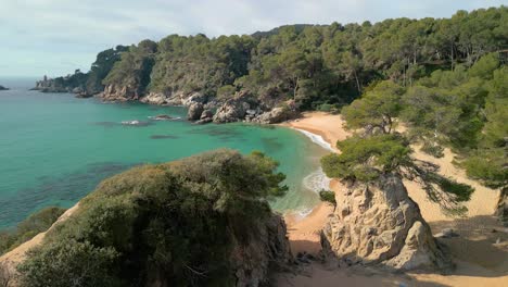 Immerse-yourself-in-the-aerial-splendor-of-Lloret-De-Mar,-where-transparent-blue-waters-meet-upscale-tourism-spots-like-Santa-Cristina-and-Cala-Treumal