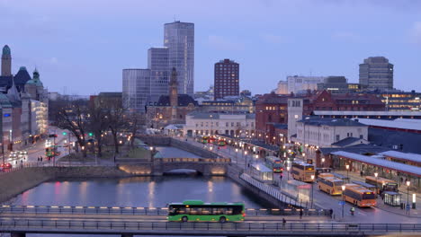 Twilight-aerial-of-buses-and-traffic-around-illuminated-Malmo-Central-Station