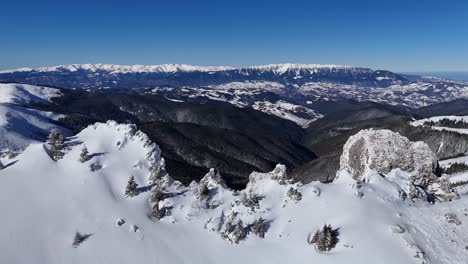 Snow-covered-Bucegi-Mountains-with-view-of-Iezer-Papusa-and-Piatra-Craiului,-aerial-shot-in-daylight