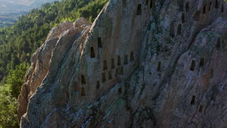 Ascending-pedestal-drone-shot-of-a-beehive-like-trapezoid-niches-of-Eagle's-Rock-or-more-commonly-known-as-Orlovi-Skali,-located-in-Rhodope-Mountain-in-the-countryside-of-Bulgaria