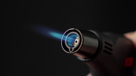 Butane-Torch-Lighter-With-Blue-Flame-and-Black-Background,-Close-Up-Shot