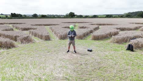 Alien-masked-person-on-Andover-crop-circle-giving-peace-sign-aerial-view-speed-ramp-to-molecular-pattern-on-wheat-farmland