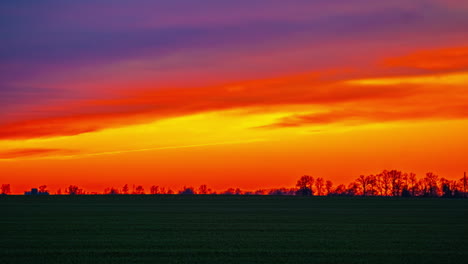 Leuchtend-Orangefarbener-Sonnenuntergang-über-Einer-Landschaft-In-Silhouette---Fließende-Wolkenlandschaft-Im-Zeitraffer