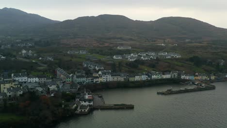 Wide-aerial-static-shot-of-Roundstone-harbour,-featuring-the-town-colourful-houses-and-mountains-in-the-background