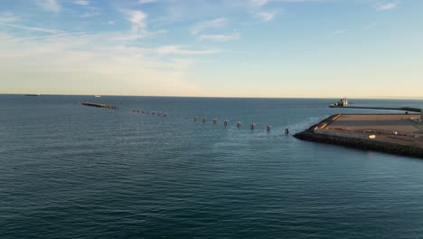 flight-with-a-drone-in-the-sea-to-a-pier-seeing-a-part-that-is-disabled-due-to-its-age,-only-the-supports-and-some-platform-remaining-we-see-a-blue-sky-with-some-clouds-on-a-winter-afternoon