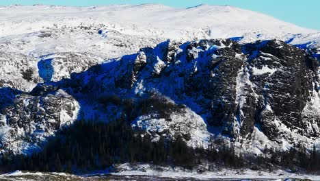 Montañas-Rocosas-Cubiertas-De-Nieve-Durante-El-Invierno-En-Bessaker,-Noruega---Disparo-Aéreo-De-Drones