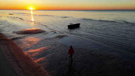 A-person-walks-along-the-sandy-and-unusual-beach-at-sunset,-where-the-terrain-is-unusual