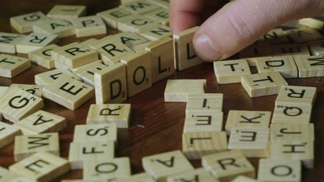 Male-hand-places-Scrabble-letter-tiles-on-edge-to-form-word-DOLLAR