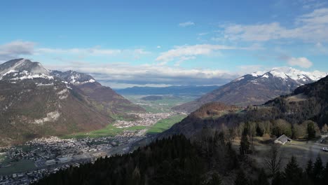 Swiss-town-sits-deep-in-grassy-valley-below-snow-covered-mountains