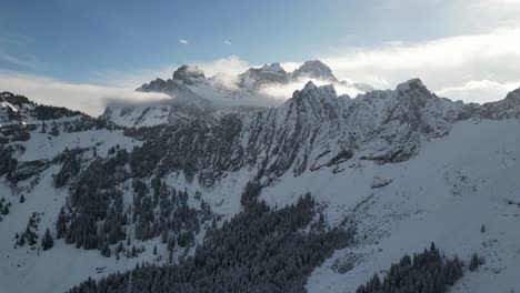 Gezackte,-Freiliegende-Bergrücken-Mit-Höheren,-Schneebedeckten-Berggipfeln-Und-Wolken-überragen-Den-Kiefernwald
