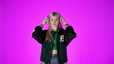 Blonde-woman-puts-on-over-ear-headphones,-isolated-purple-background,-studio