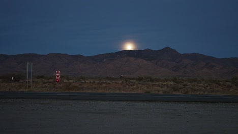 Zeitraffervideo-Des-Mondaufgangs-über-Einer-Bergkette-Mit-Vorbeifahrenden-Fahrzeugen-In-Nevada