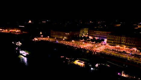 People-gathering-in-Quai-du-Maréchal-square-during-Wine-Fair-at-night-in-Bordeaux-France,-Aerial-pan-right-shot