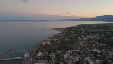 Establishing-aerial-drone-shot-of-Loreto-Mexico-Baja-California-Sunset-Skyline-City-Town-vibrant-Travel-destination-in-Latin-America,-golden-hour,-houses-and-streets-of-Mexican-oceanside