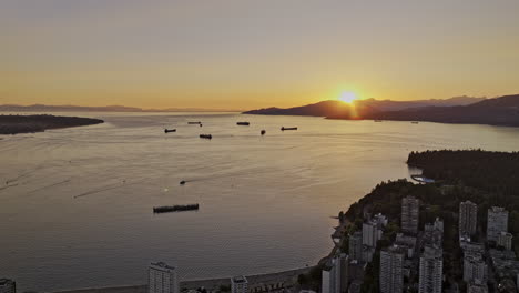Vancouver-BC-Canada-Aerial-v62-reserve-flyover-West-End-neighborhood-capturing-English-bay-beach,-Burrard-inlet,-mountain-and-views-of-the-sunset-over-the-bay---Shot-with-Mavic-3-Pro-Cine---July-2023