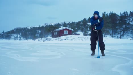 El-Hombre-Está-Empleando-Una-Barrena-Manual-Para-Perforar-Un-Lago-Congelado-Para-Pescar-En-El-Hielo-En-Bessaker,-Condado-De-Trondelag,-Noruega---Toma-Estática