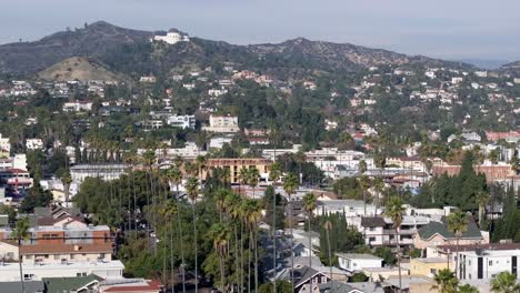 Iconic-Los-Angeles-view-of-palm-tree-lined-streets,-Griffith-Observatory-and-Hollywood-Hills,-aerial