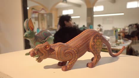 Dos-Esculturas-Talladas-En-Madera-Que-Representan-Figuras-De-Alebrije,-Una-Artesanía-Originaria-De-México,-Exhibidas-En-Un-Taller-De-Artesanía.