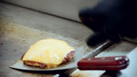 4K-Cinematic-food-cooking-footage-of-a-chef-preparing-and-making-a-delicious-homemade-burger-in-a-restaurant-kitchen-in-slow-motion-and-getting-the-cheese-beef-burger-off-the-grill