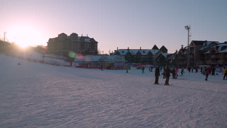 Skiers-and-lodge-at-Alpensia-Ski-Resort,-Korea,-wide-angle-view-at-sunset