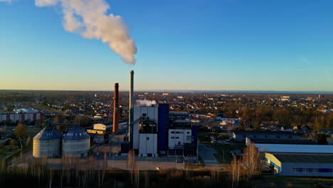 Steam-from-a-district-heating-station-smokestack-in-a-European-town---aerial-orbit